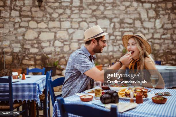 young tourists couple eating meze at traditional greek restaurant - greek food imagens e fotografias de stock