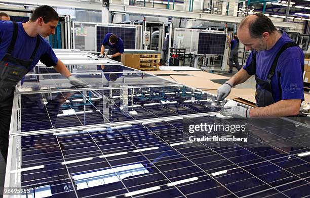 Employees Sebastian Franz, left, and David Wolfram polish a solar panel at the Solarworld AG plant in Freiberg, Germany, on Monday, Feb. 8, 2010....
