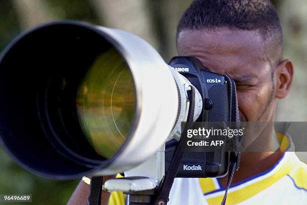 Jerson Gonzalez of Colombia, peers through a camera lens, 24 July 2001, during a practice session in Armenia, Colombia. Colombia will face Honduras...