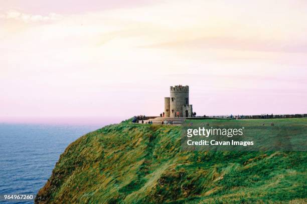 tourist visiting obrien tower on cliffs of moher by sea against cloudy sky - ireland castle stock pictures, royalty-free photos & images