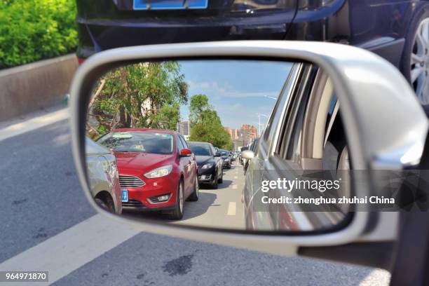 car mirror shows row of cars traffic jam - vista dalla parte posteriore di un veicolo foto e immagini stock