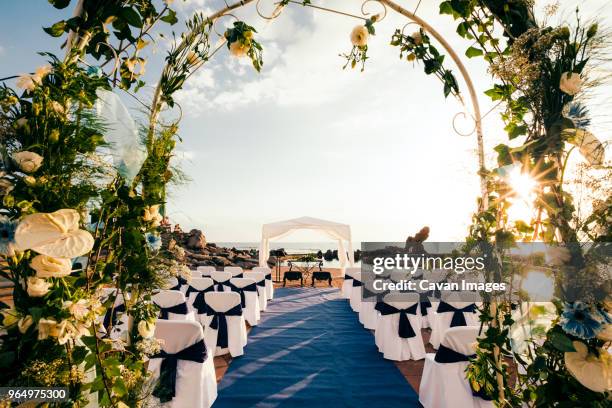 chairs arranged for ceremony seen through wedding arch - cérémonie du mariage photos et images de collection