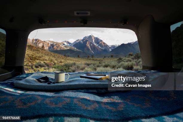 book and mug on blanket at car trunk with mount morrison in background - car trunk fotografías e imágenes de stock