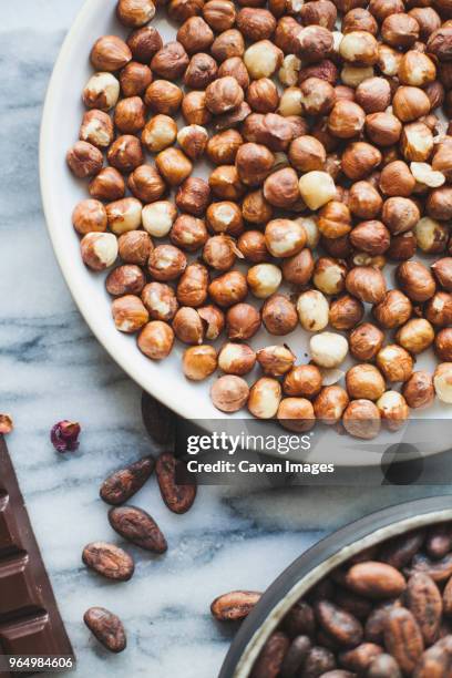 high angle view of hazelnuts with coco beans on kitchen counter - coco brown stock pictures, royalty-free photos & images