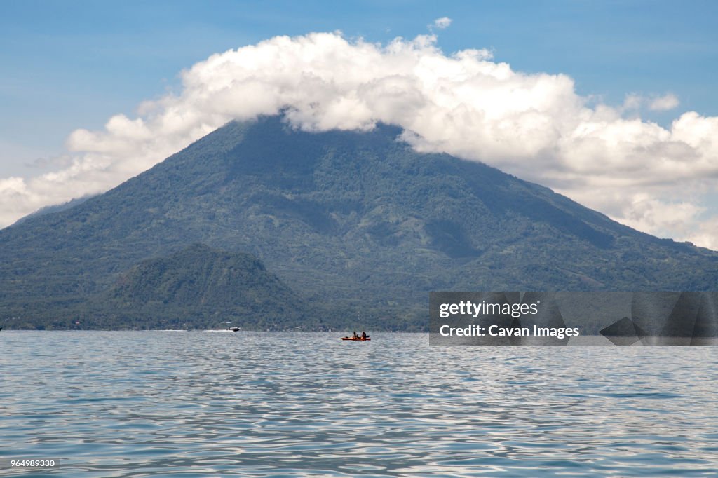 Scenic view of Lake Atitlan against mountains and cloudy sky