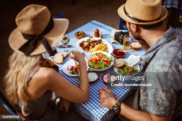 young tourists couple eating traditional greek food at rustic restaurant - cyprus stock pictures, royalty-free photos & images