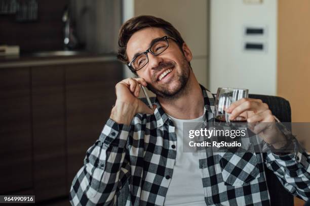 young man talking on phone and drinking at home - letting it all hang out stock pictures, royalty-free photos & images