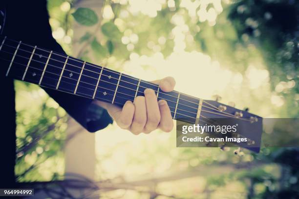 cropped image of man playing guitar - plucking an instrument - fotografias e filmes do acervo