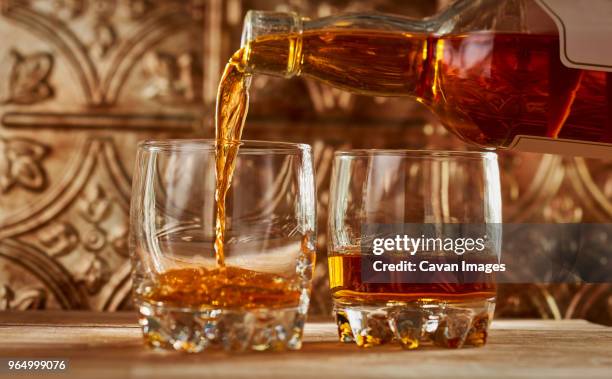 close-up of whiskey being poured into glass on table - scotch whisky stock-fotos und bilder