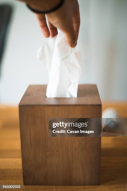 cropped hand of person removing tissue paper from box on table - box of tissues stock pictures, royalty-free photos & images