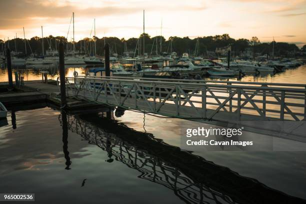 sailboats moored on lake at harbor against sky during sunset - mamaroneck stock pictures, royalty-free photos & images