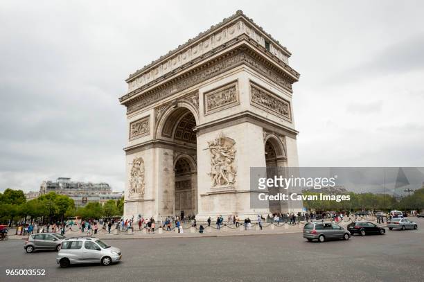 tourist visiting arc de triomphe against cloudy sky in city - arc de triomphe stock-fotos und bilder