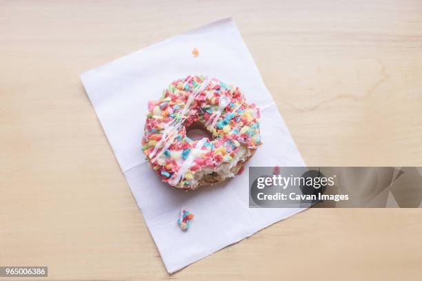 high angle view of eaten donut on paper at table - sugar sprinkles stock pictures, royalty-free photos & images