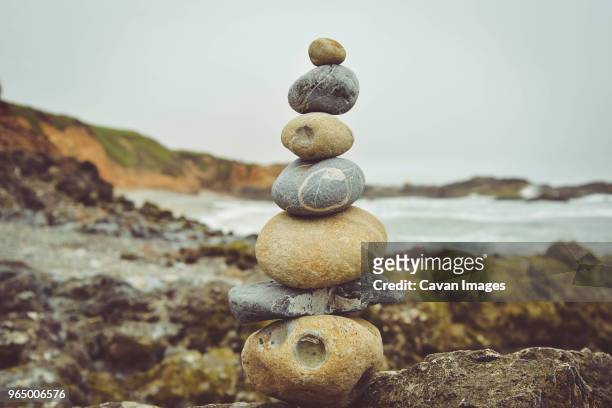 stacked stones on rocks at beach against sky - pescadero stock pictures, royalty-free photos & images