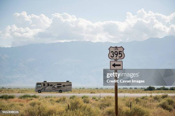 tour bus on country road against cloudy sky with directional sign in foreground - bus tour guide stock pictures, royalty-free photos & images