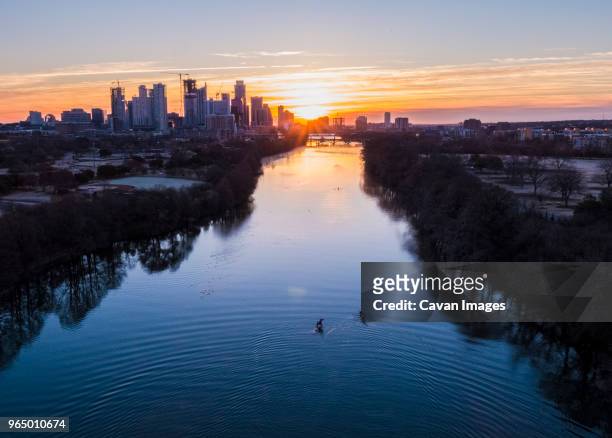high angle distant view of people sculling on lady bird lake against cityscape during sunrise - sweep rowing bildbanksfoton och bilder