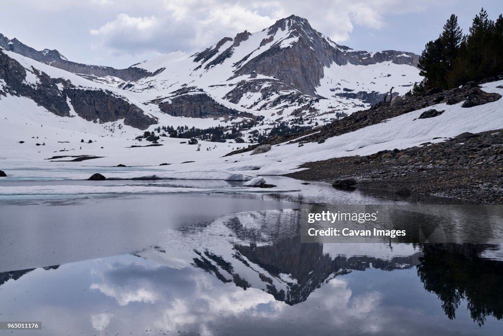 Scenic view of snow covered mountains reflecting on calm lake