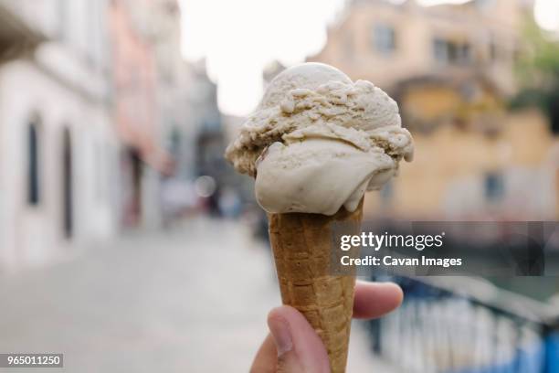 cropped hand of person holding gelato ice cream in city - gelato fotografías e imágenes de stock