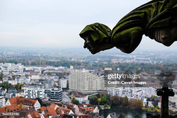 gargoyle of ulm minster church by cityscape against sky - ulmer münster stock-fotos und bilder