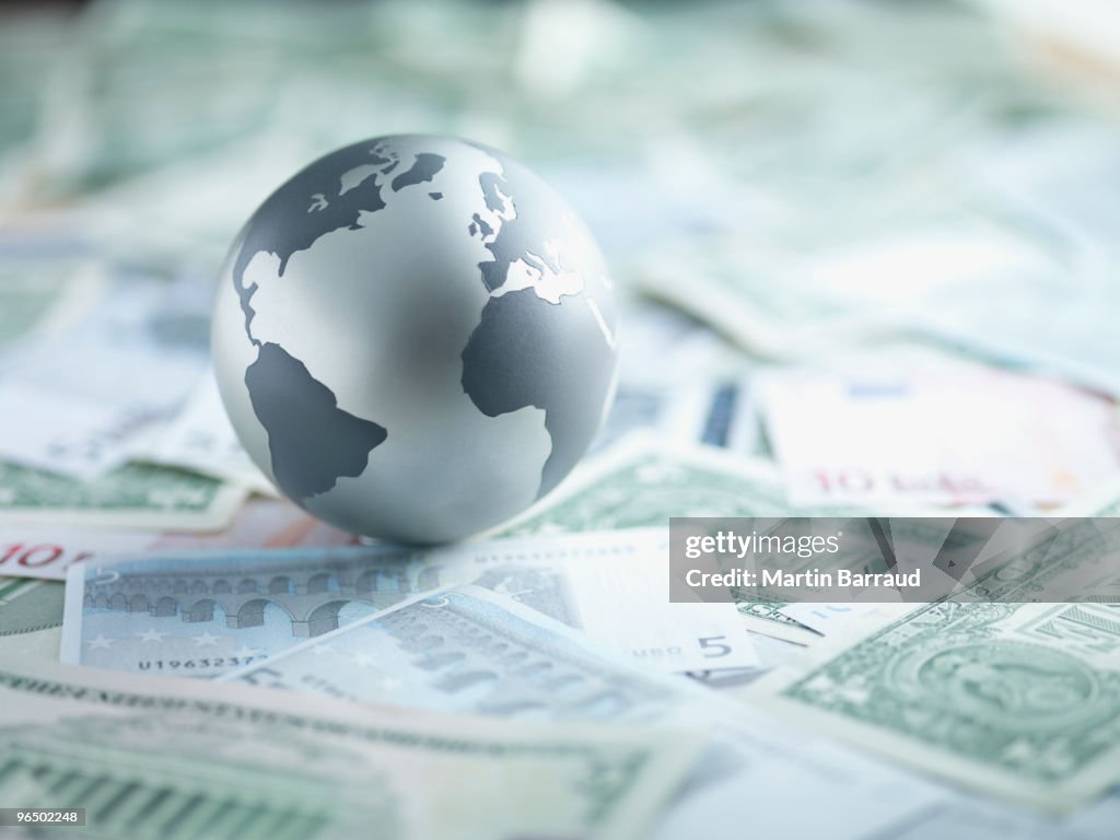 Metall-globe ruhen auf Papier Währung