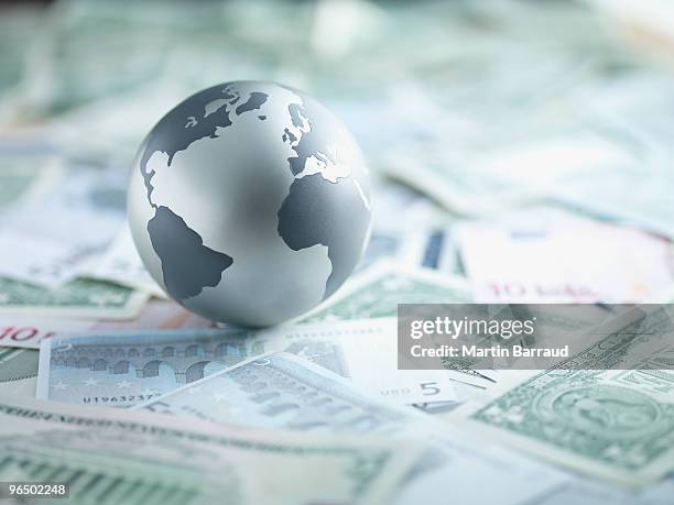 metal globe resting on paper currency - global connections stock pictures, royalty-free photos & images