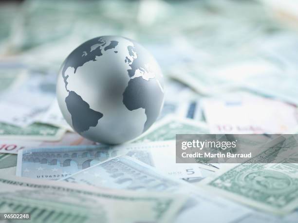 metal globe resting on paper currency - globalization stock pictures, royalty-free photos & images