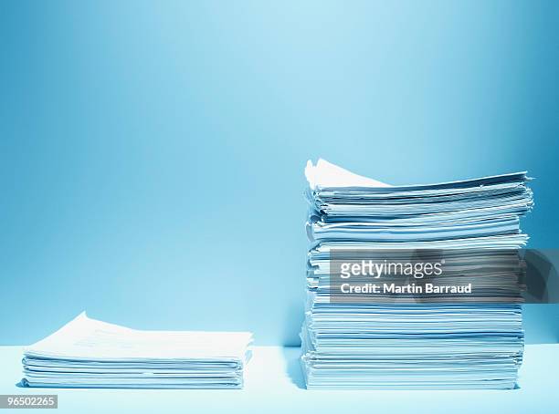 tall and short stacks of paper - pile of paper stockfoto's en -beelden