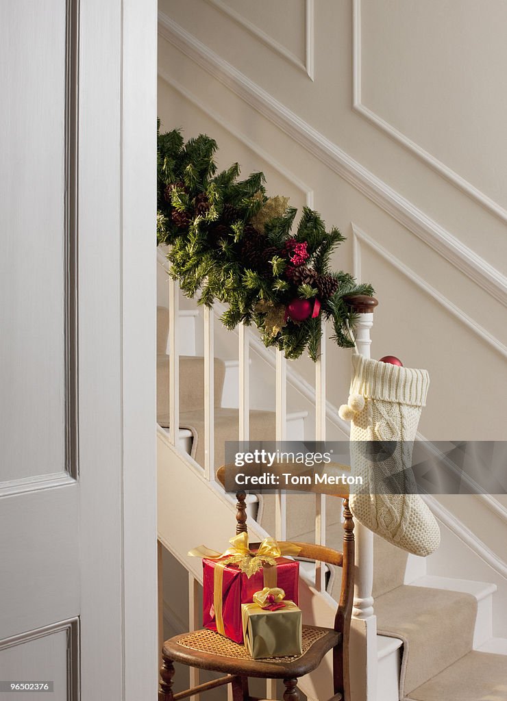 Christmas gifts and stocking near staircase