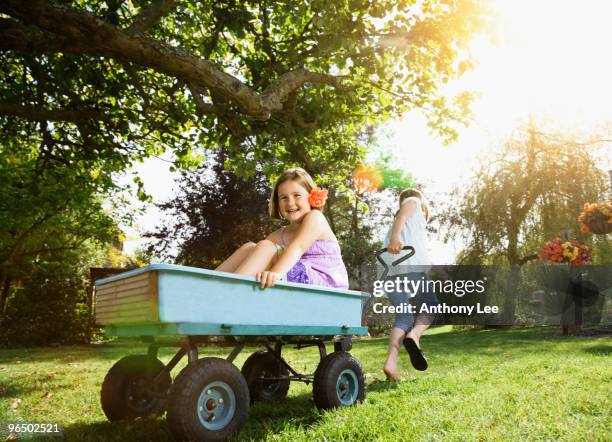 girl pulling girl in wagon - toy wagon stock pictures, royalty-free photos & images