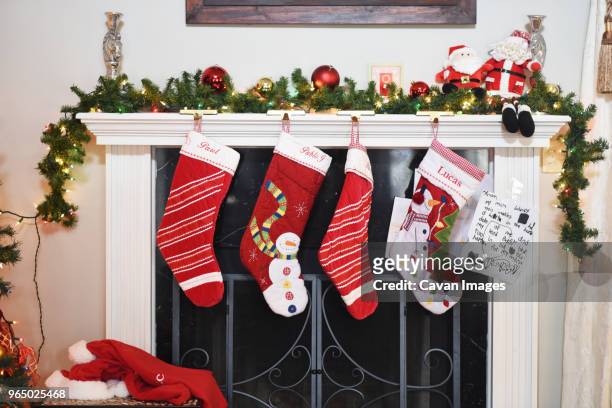 christmas stockings hanging by fireplace at home - stockings stockfoto's en -beelden
