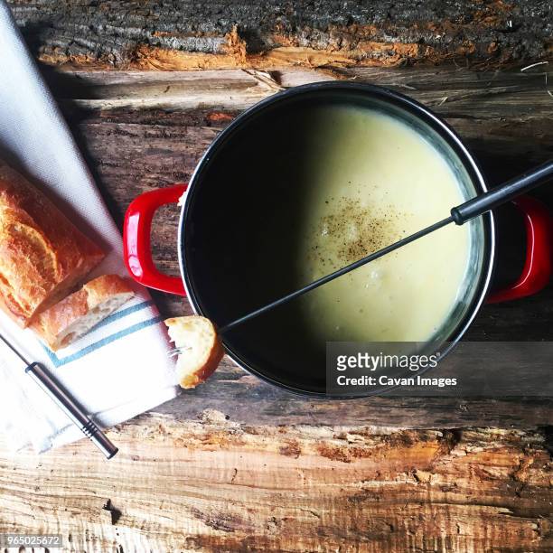 overhead view of bread with cheese fondue on wooden table - cheese fondue stock pictures, royalty-free photos & images