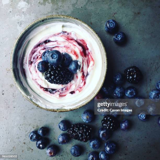 overhead view of berry fruits and syrup on yoghurt - joghurt stock-fotos und bilder