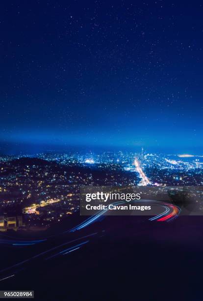 majestic view of light trails on winding road against star field - winding road night stock pictures, royalty-free photos & images