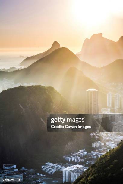 view of sunlight falling on mountains by residential buildings in morning - center of gravity 2017 stock pictures, royalty-free photos & images