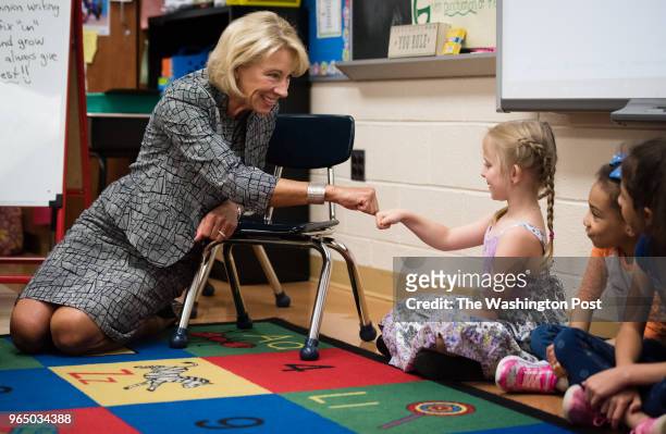 Education Secretary Betsy DeVos gives a morning meeting fist pump greeting to first grader, Annabelle Devouin. She and other Trump administration...