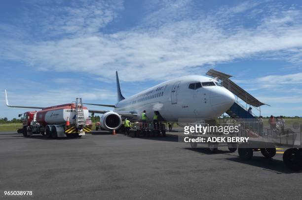 Workers unload luggage from a Sriwijaya Air flight at the Fatmawati airport in Bengkulu on June 1, 2018. - Sriwijaya Air is an Indonesian carrier and...