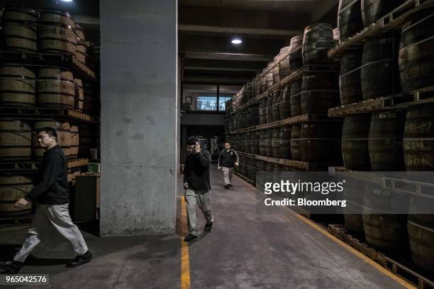 Employees walk past wooden barrels in a warehouse at the Kavalan Single Malt Whisky distillery in Yilan County, Taiwan, on Thursday, Jan. 25, 2018....