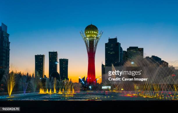 illuminated bayterek tower and fountain in city against clear blue sky - kazakhstan foto e immagini stock