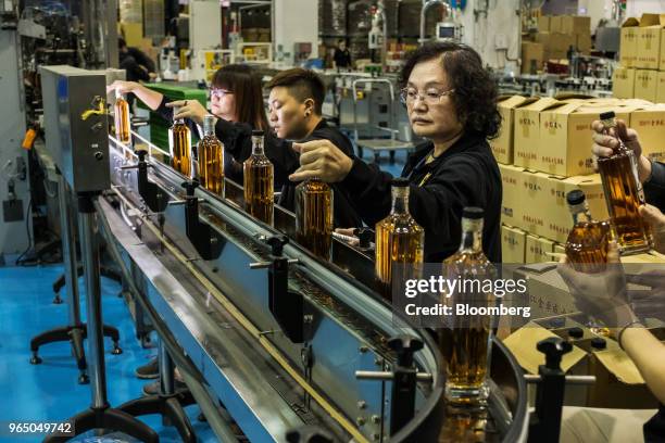 Employees collect bottles of Kavalan whisky from a conveyor for packaging at the Kavalan Single Malt Whisky distillery in Yilan County, Taiwan, on...