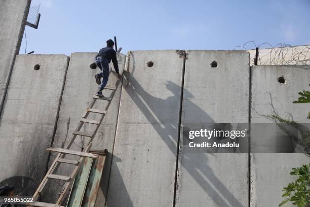 Palestinians climb the ladders to cross the separation wall to reach Jerusalem in order to perform the third Friday Prayer of Islamic holy month of...