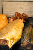 Smoked fish, mackerel, sig, perch and cod roe on the black wooden table. Omega 3 source. Polyunsaturated fats