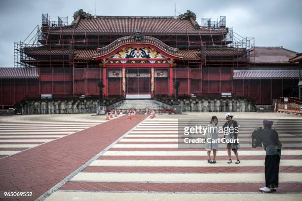 Tourists have their photograph taken by a guide in traditional Okinawan dress as they visit Shuri Castle on June 1, 2018 in Naha, Japan. Like the...