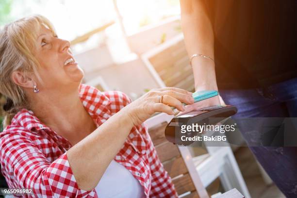 senior vrouw mobiel betalen in café - bakibg stockfoto's en -beelden