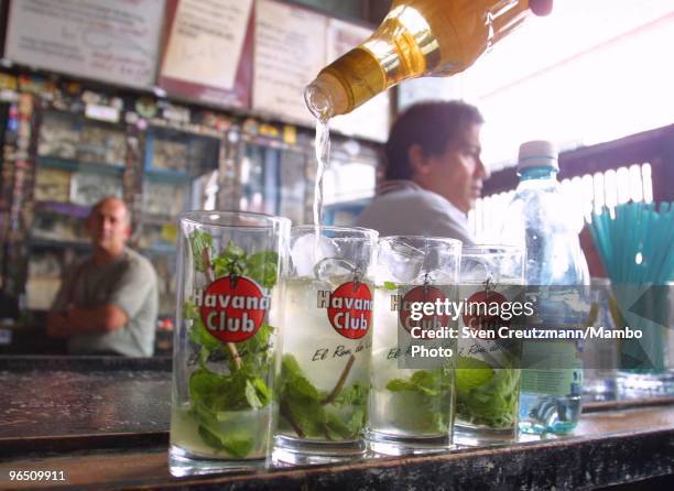 Havana Club rum is being poured into glasses to make the Mojito, a typical Cuban rum cocktail, stand at the bar of the Bodeguita del Medio bar and...