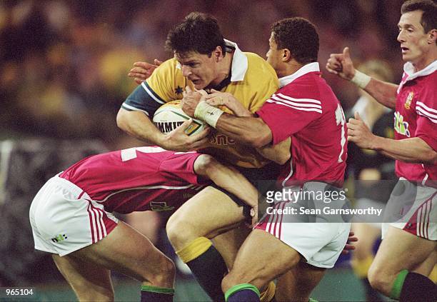 Matt Burke of Australia is tackled by Rob Henderson and Jason Robinson of the British Lions during the British and Irish Lions tour match against...