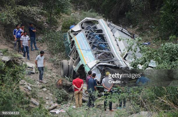Rescue personnel and onlookers stand around a bus afer it fell off a mountain road into a deep gorge killing seven passengers near Gajerhi, some 42...