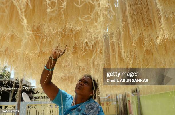 An Indian worker arranges strands of vermicelli noodles to dry at a factory during on the outskirts of Chennai on June 1, 2018. - Sheer khurma, or...