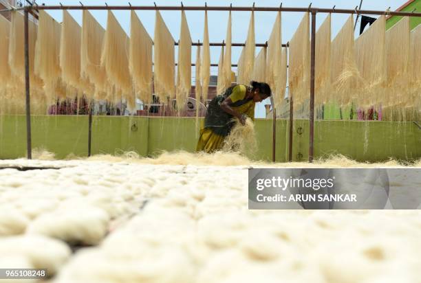 An Indian worker arranges strands of vermicelli noodles to dry at a factory during on the outskirts of Chennai on June 1, 2018. - Sheer khurma, or...