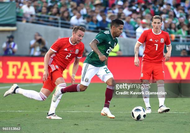 Javier Aquino of Mexico is chased by Chris Gunter as teammate Harry Wilson of Wales looks on during the first half of their friendly international...