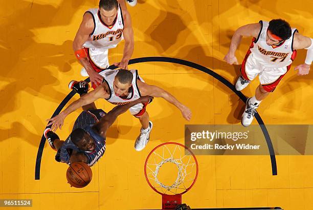 Raymond Felton of the Charlotte Bobcats shoots a layup against Stephen Curry, Andris Biedrins and Vladimir Radmanovic of the Golden State Warriors...